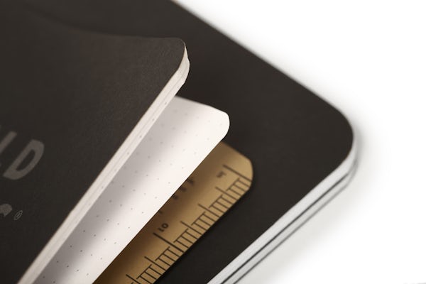 A close-up of the Pitch Black Notebook, slightly opened, showing the dot-graph paper style and the ruler on the back cover.